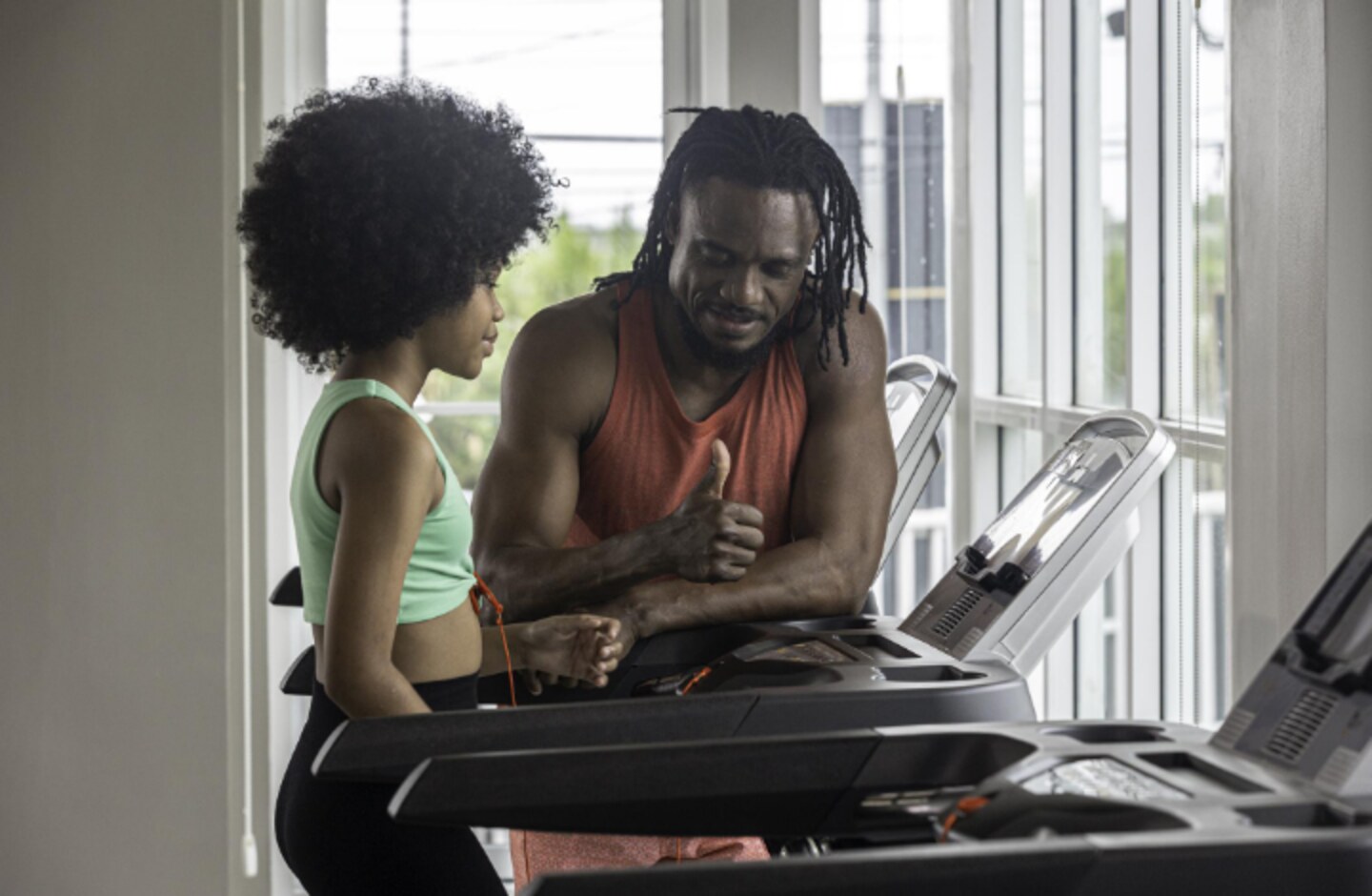 A fitness coach guiding a client through a treadmill session